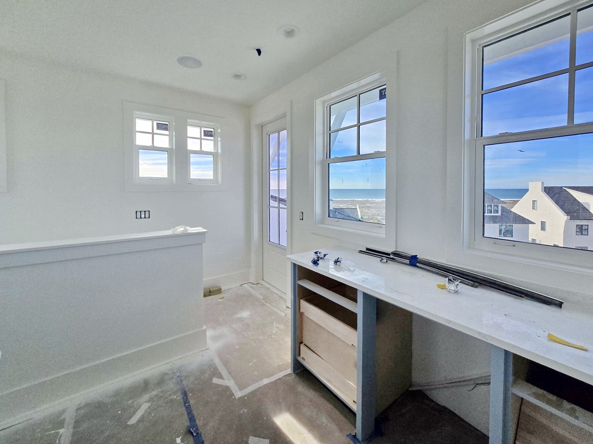Soak in your private tub while gazing at stunning ocean views through floor-to-ceiling windows in this bright, serene bathroom.