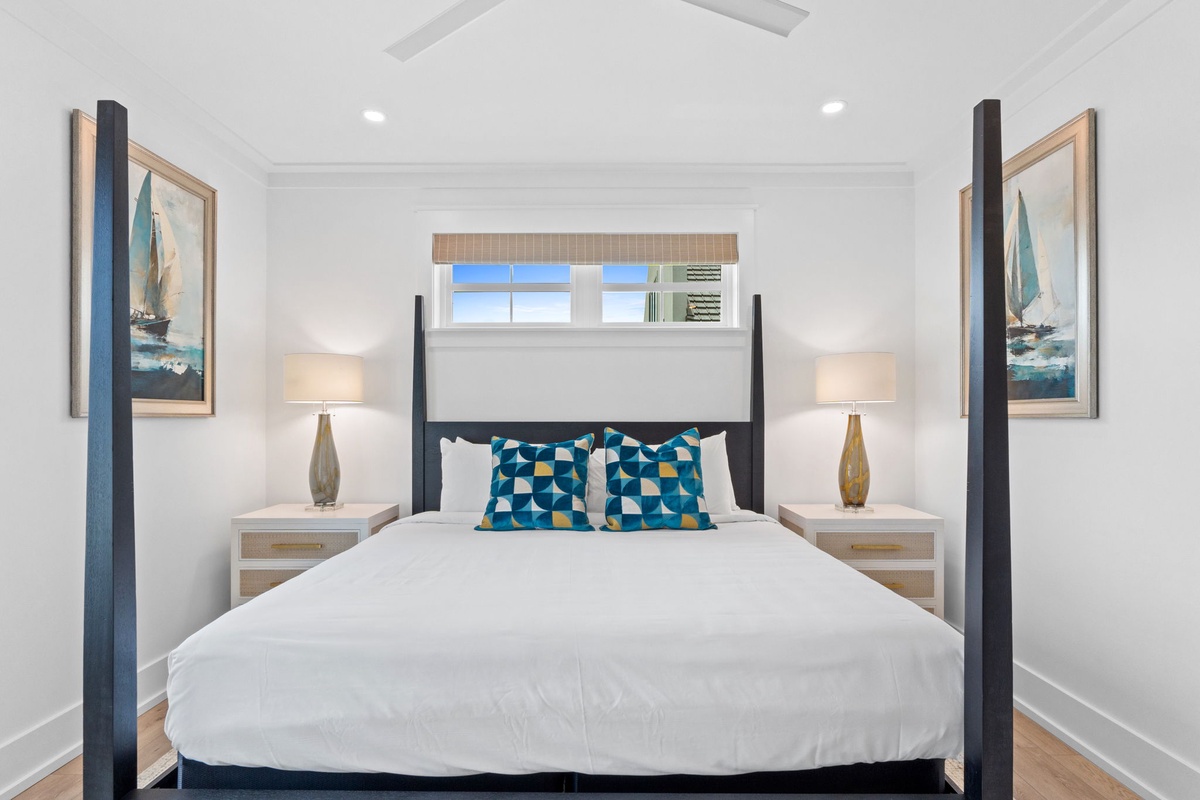 Sink into crisp white linens and coastal charm in this serene bedroom, where nautical artwork and soft bedside lighting create your perfect retreat after a day exploring.