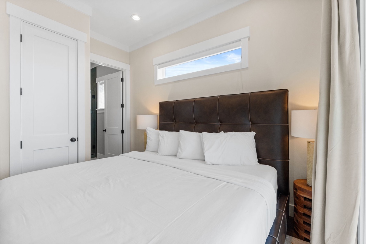 Sink into this plush king bed with crisp white linens and a tufted headboard. Natural light flows in while warm bedside lighting creates your perfect retreat.