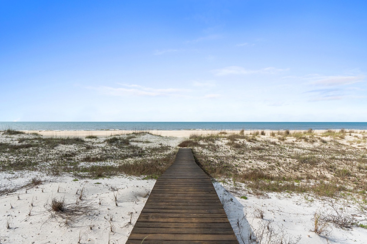 A wooden boardwalk leads through pristine sand dunes to the Gulf Coast shoreline, providing easy beach access near the property.