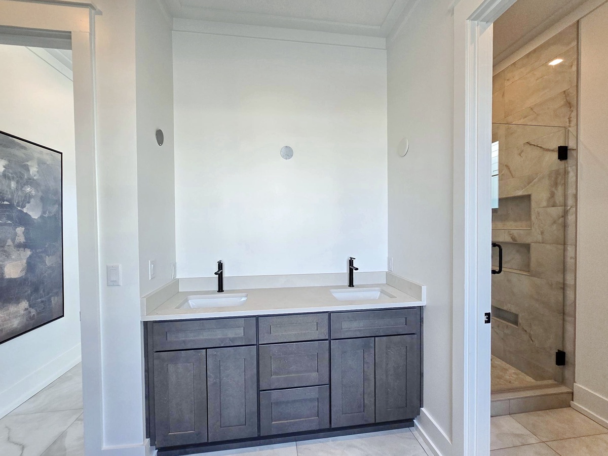 Unwind in your spacious bathroom featuring dual sinks and a luxurious glass-enclosed shower with elegant marble-style finishes.