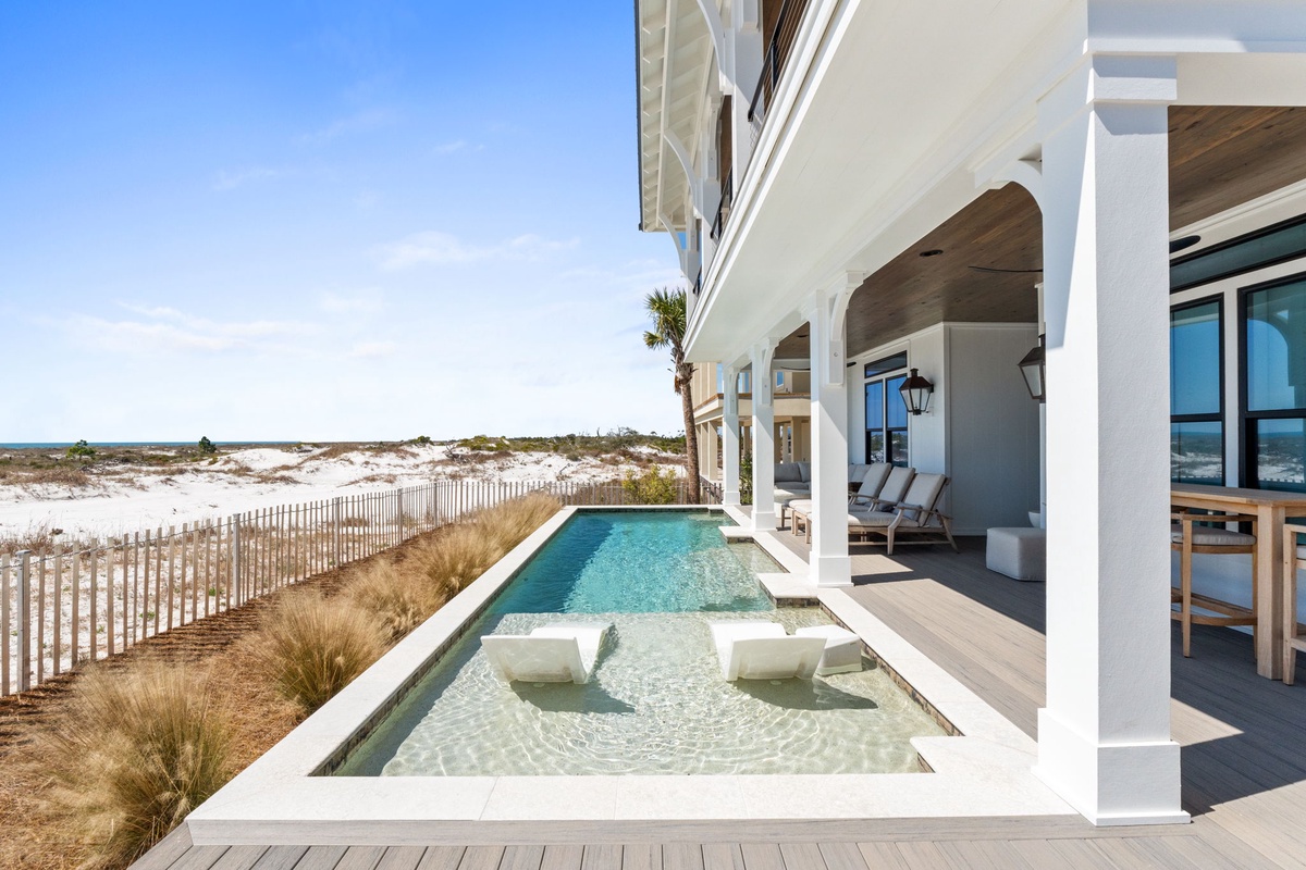 Modern beachfront property featuring a pristine pool and spa overlooking white sand dunes and natural coastline.