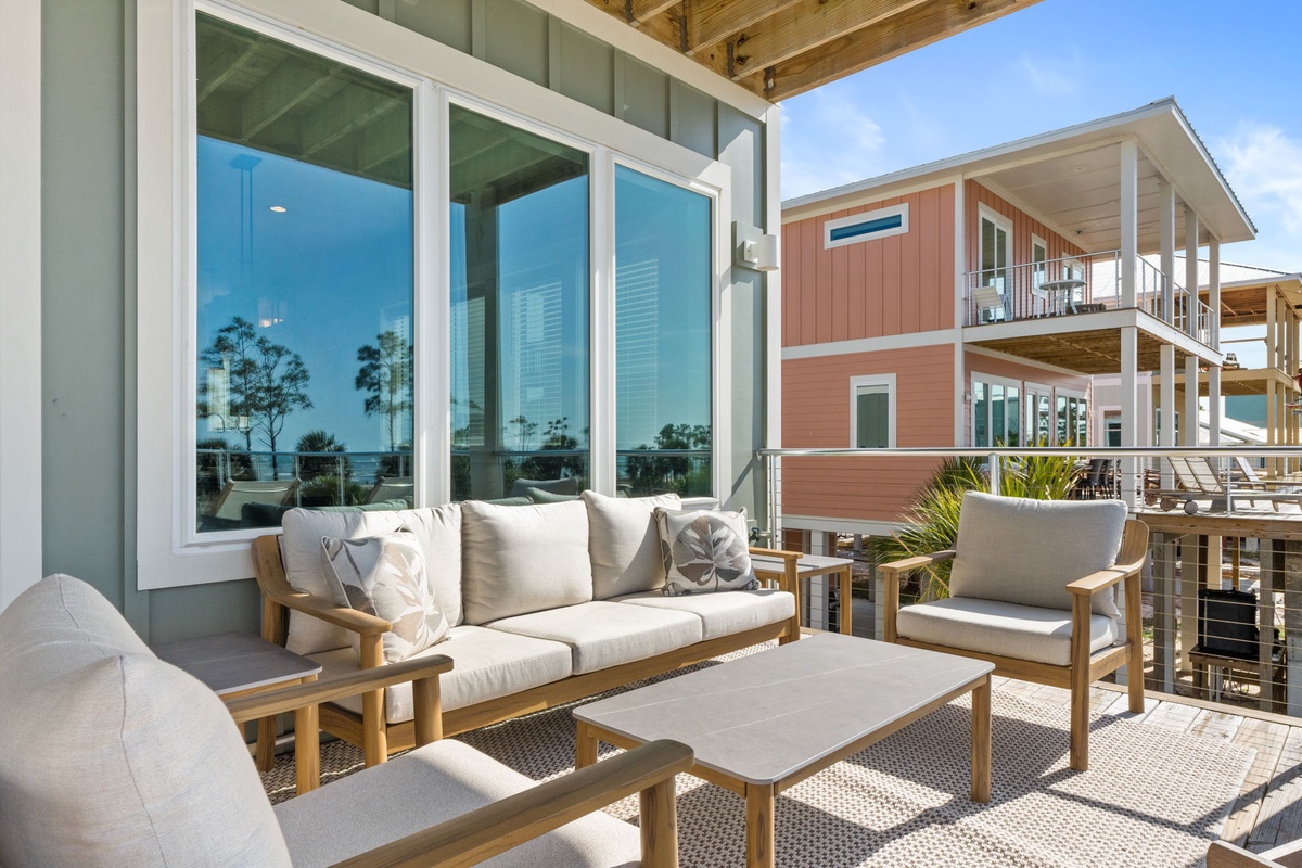 Sink into plush outdoor seating with ocean reflections dancing across the windows, creating your perfect coastal retreat.