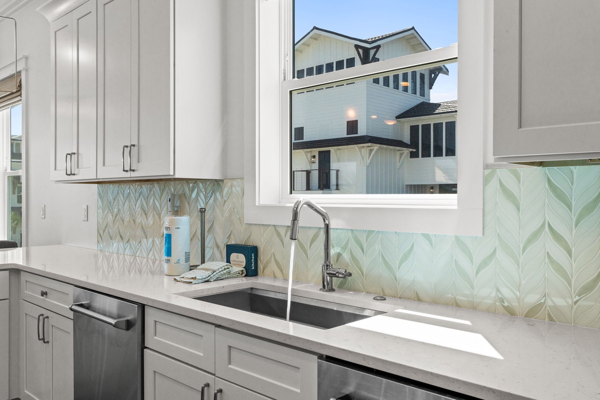 Rinse fresh veggies or prep your morning coffee at this sleek sink, where soft coastal hues and crisp white cabinetry create a calming kitchen vibe.