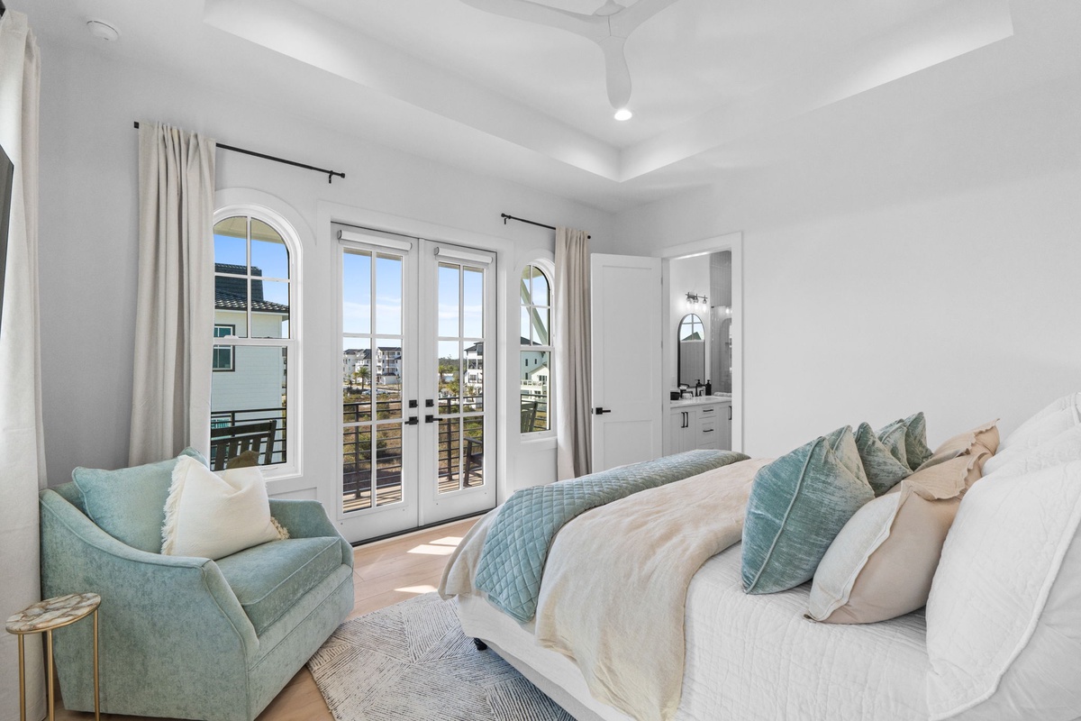 Unwind in this serene master bedroom where soft teal accents complement crisp white linens, while French doors open to your private balcony.