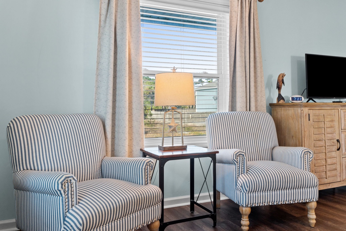 Sink into comfortable striped armchairs by your window, where natural light creates the perfect reading nook with peaceful neighborhood views.