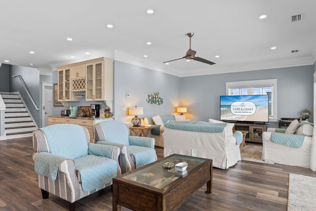 Unwind in your coastal living room with plush seating, calming blue accents, and modern entertainment - perfect for memorable evenings together.