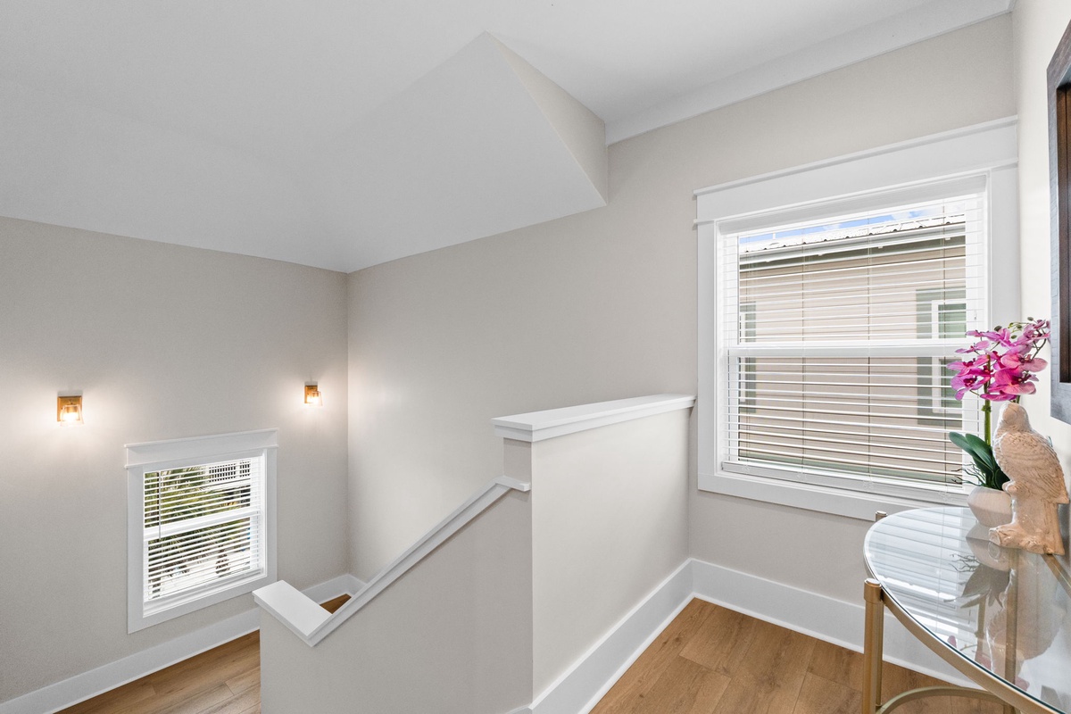 Sunlight filters through shuttered windows in this peaceful upstairs landing, where vaulted ceilings and soft gray walls create a calm retreat for your stay.