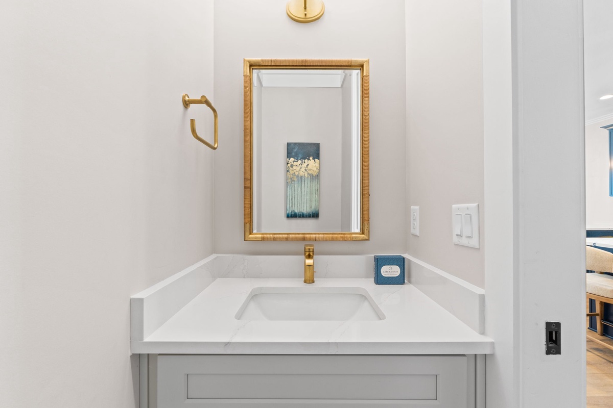 Freshen up at your elegant bathroom vanity, featuring a chic gold-framed mirror and luxurious fixtures that blend modern comfort with coastal style.