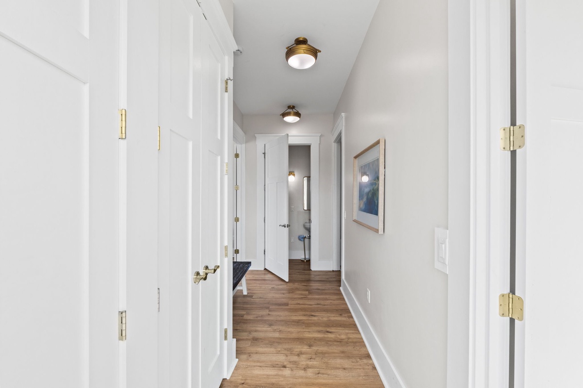 Step into your bright, welcoming hallway with warm wood floors and stylish brass fixtures guiding you to comfortable spaces ahead.