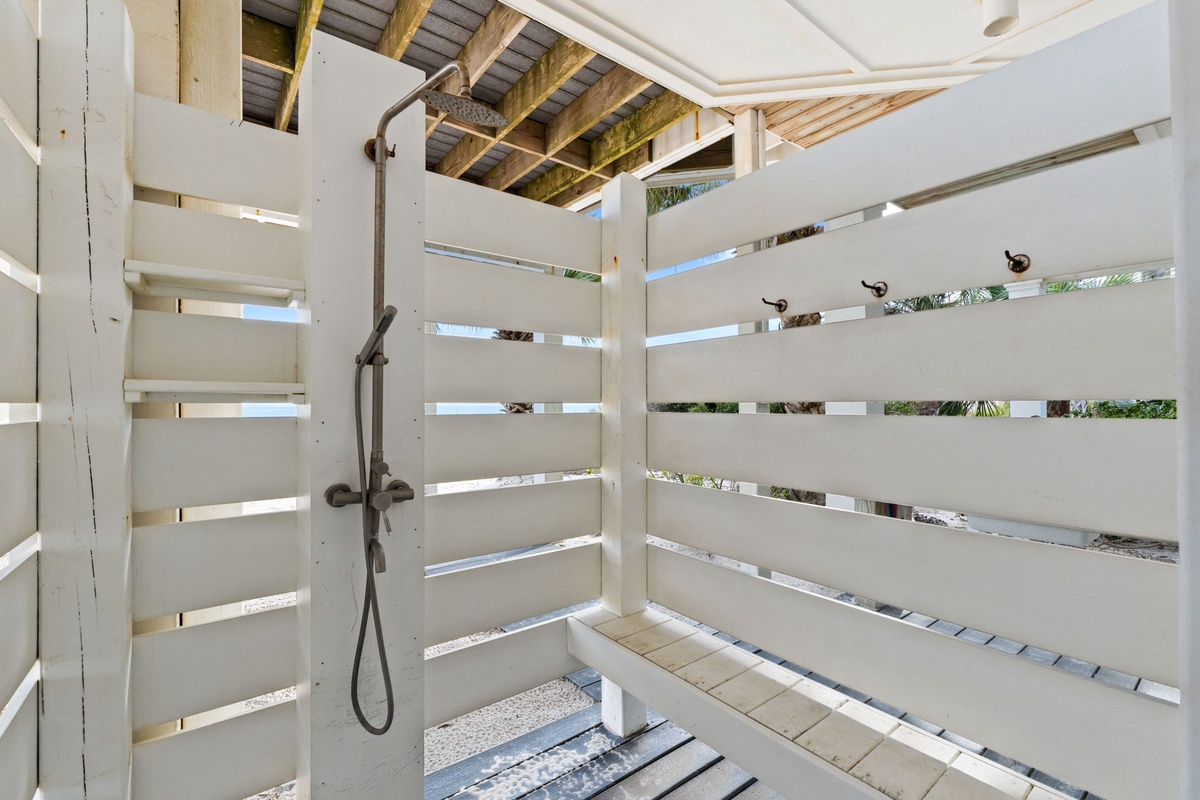 Refresh under your private outdoor shower, surrounded by tropical greenery and natural light filtering through stylish slat walls.