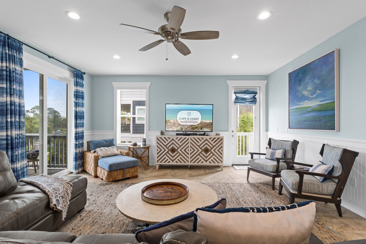 Picture yourself unwinding in this serene coastal living room with soothing blue tones, plush seating, and refreshing breeze from the ceiling fan overhead.