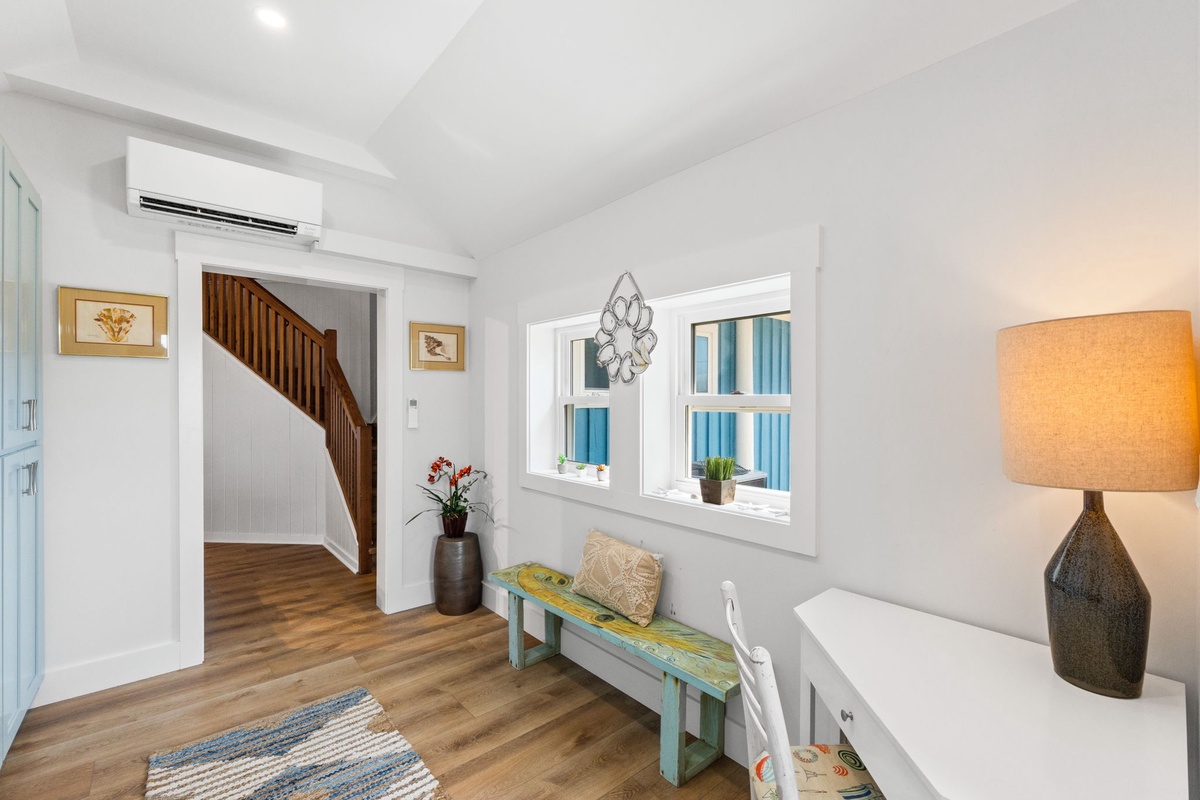 Step into your bright, welcoming entryway where coastal charm meets modern comfort. You'll find thoughtful touches throughout this airy space, from the warm wood floors to the cheerful pops of color inviting you to settle in.
