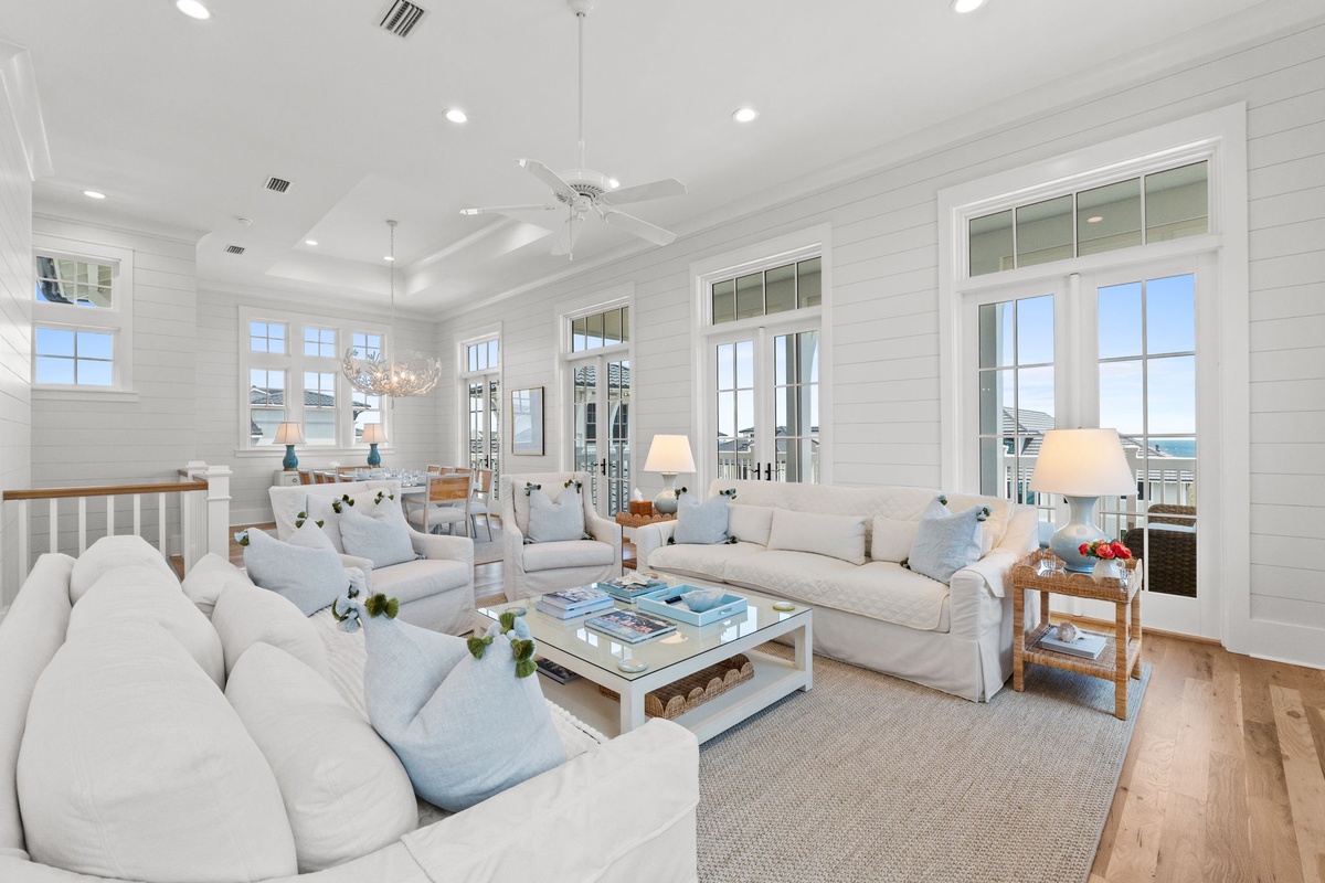 Settle into plush sofas with ocean breezes flowing through French doors. Your bright, coastal living room invites effortless relaxation with soaring ceilings and serene views.