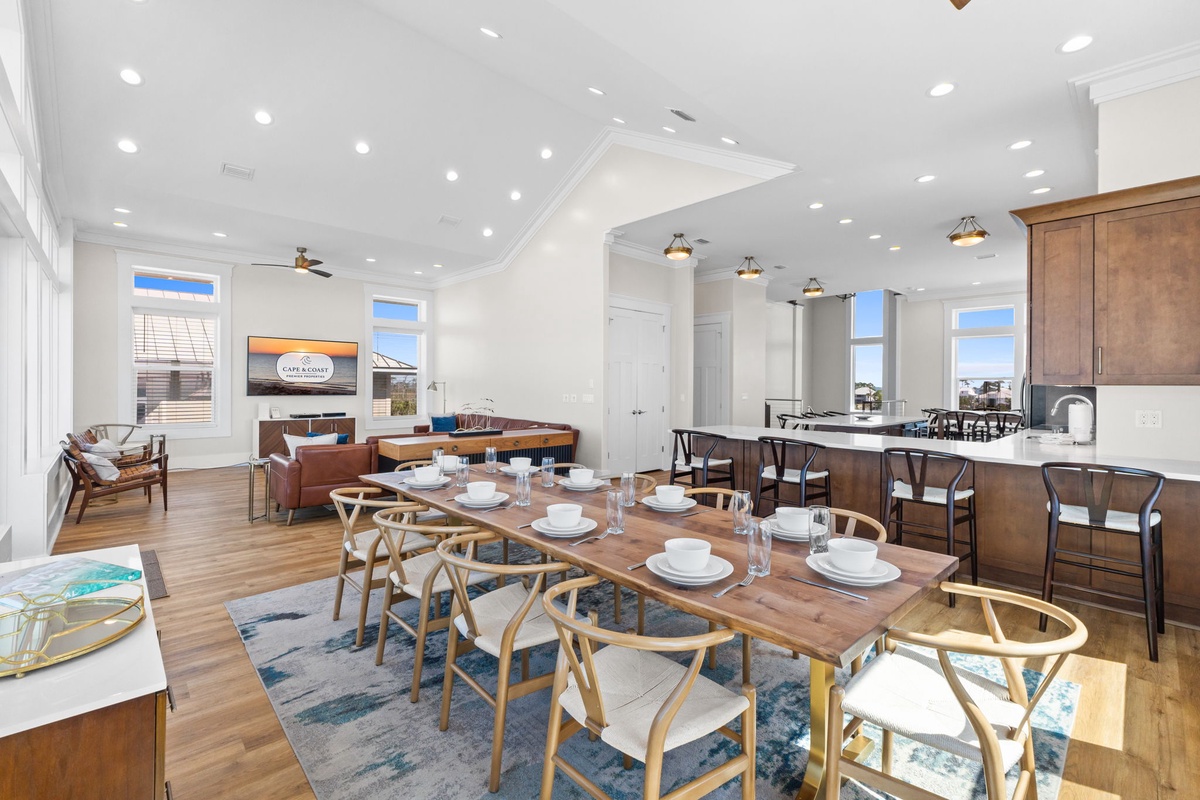 Your open-concept living space combines dining, kitchen, and lounge areas with soaring ceilings and natural light streaming through expansive windows.