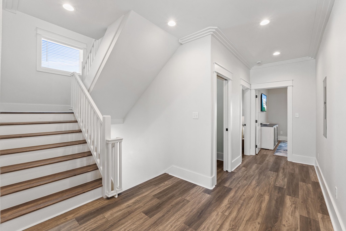 A bright, open hallway welcomes you with gleaming wood floors, clean white walls, and abundant natural light—your peaceful path to relaxation.