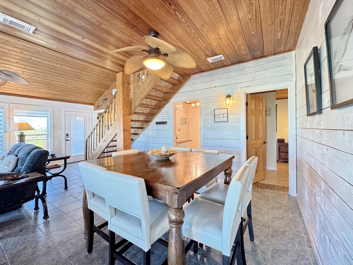 Gather around your rustic dining table beneath beautiful wood ceilings, where warm lighting creates the perfect atmosphere for meals.