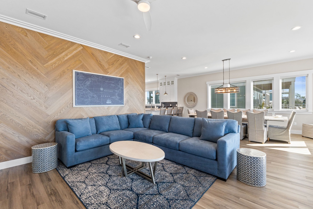 Unwind in your spacious living area with plush blue sectional seating and stunning wood accent wall, perfect for relaxing after exploring the city.
