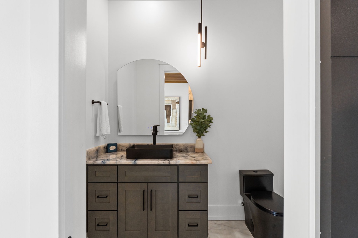 Step into this modern bathroom featuring a sleek vessel sink atop a marbled vanity, paired with contemporary black fixtures and abundant natural light.