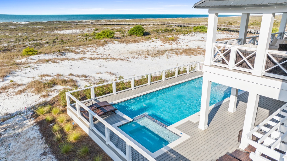 Stunning beachfront property featuring a sparkling pool deck overlooking pristine coastal dunes and turquoise waters.
