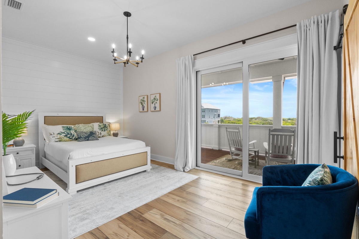 Step into your serene coastal retreat with a plush bed, modern chandelier, and private balcony overlooking endless ocean views—your perfect escape awaits.
