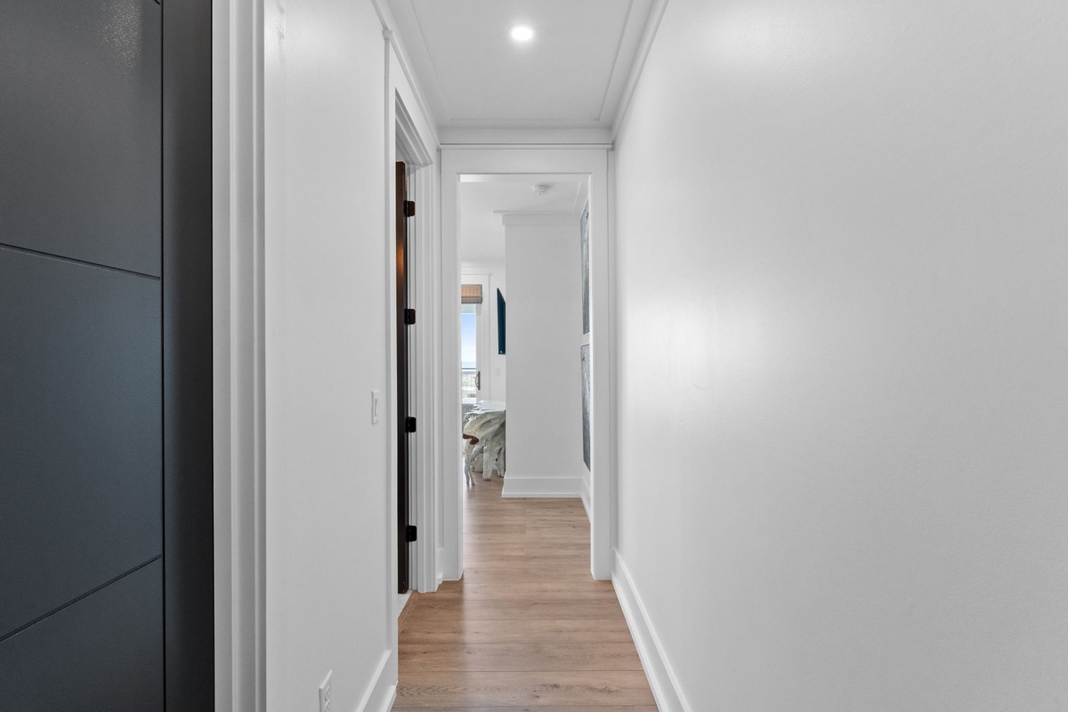 Step through this bright hallway into your peaceful retreat, where warm wood floors and crisp white walls create a welcoming path to your private spaces.
