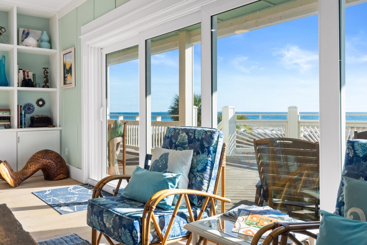 Unwind in your bright coastal living room where ocean breezes flow through open doors to your private deck overlooking endless blue waters.