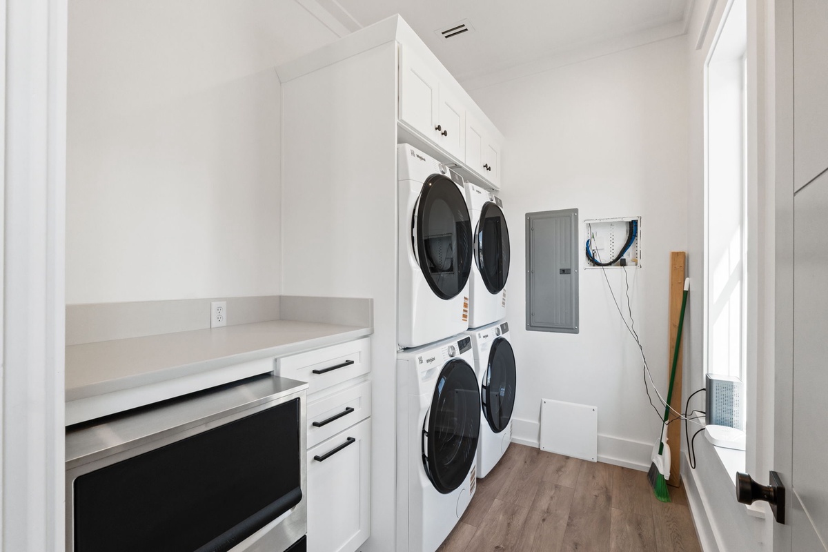 Keep your wardrobe fresh in this pristine laundry room with stacked washer and dryer, built-in storage, and convenient countertop workspace.