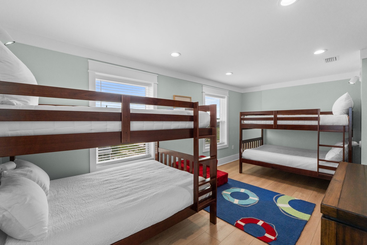 Your little ones will love this cheerful bunk room, with two sturdy wooden bunks offering cozy sleeping spaces for four. Soft linens and a playful nautical rug complete the space.
