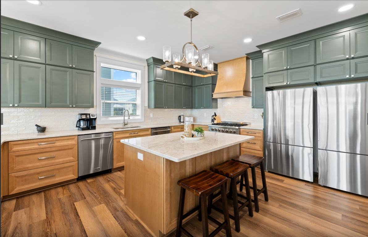 Your gourmet kitchen features stunning green cabinetry, warm wood accents, and premium stainless appliances—perfect for preparing memorable meals during your stay.