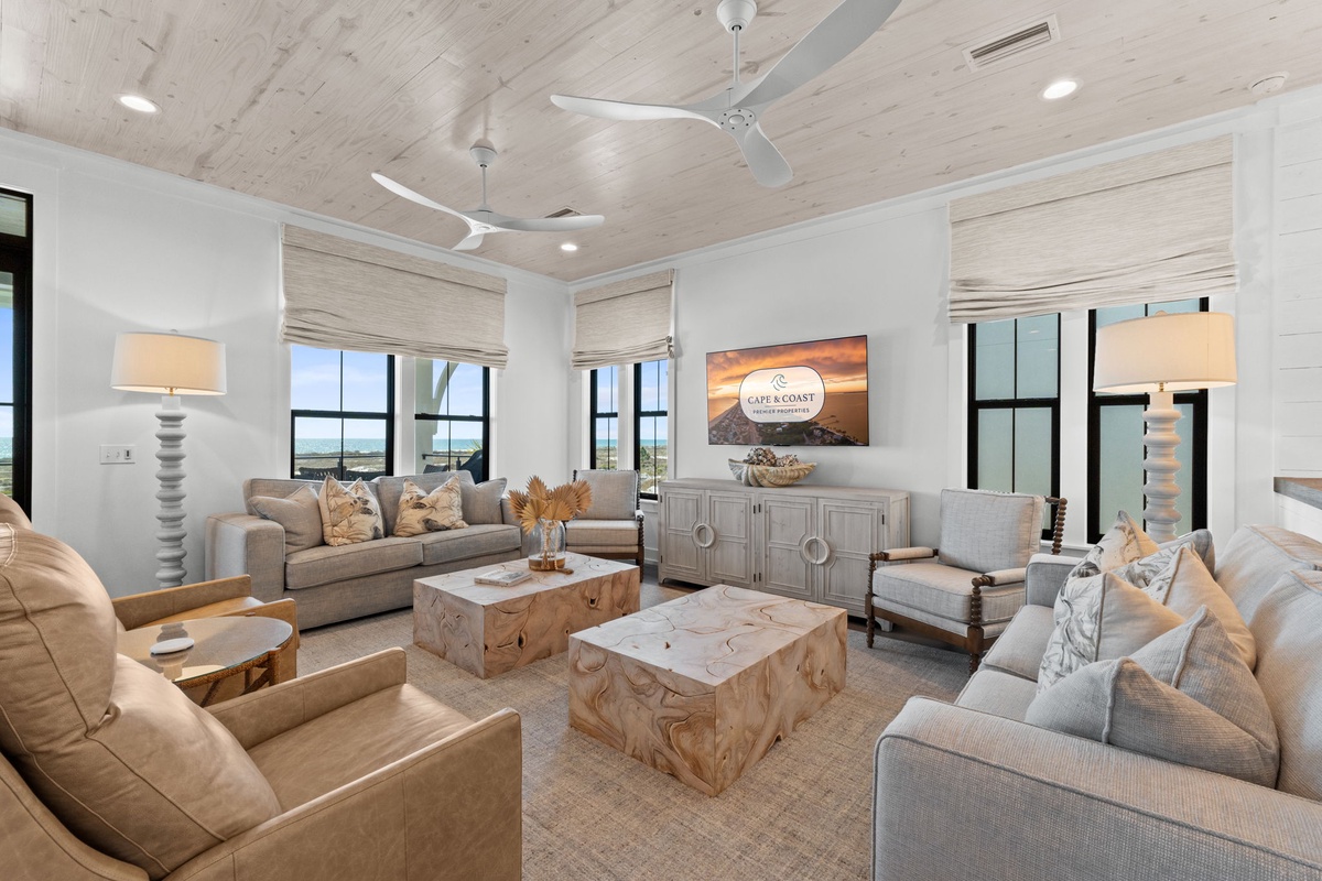 Unwind in this sophisticated living space with plush seating, ocean views through floor-to-ceiling windows, and natural coastal decor.