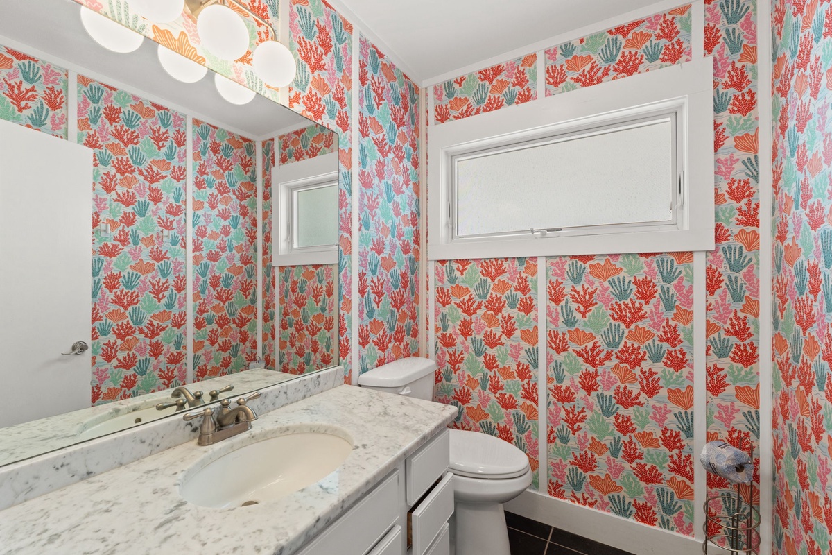 Refresh in your private bathroom adorned with vibrant coral and shell wallpaper, featuring a marble vanity, gleaming fixtures, and a walk-in shower that invites relaxation after a sun-soaked day.