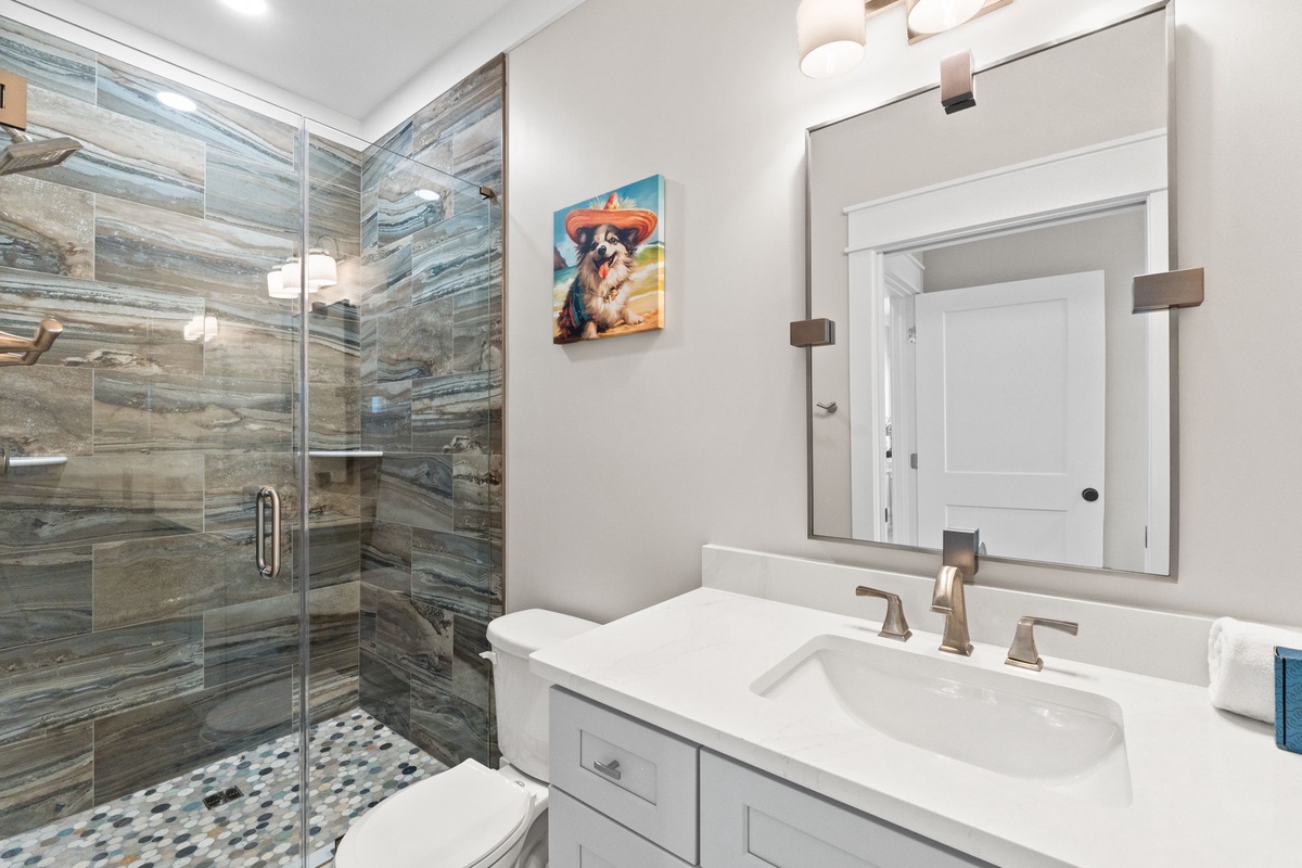 Step into your serene, spa-like retreat featuring a stunning walk-in shower with rich wood-look tile and a bright vanity that invites you to unwind.