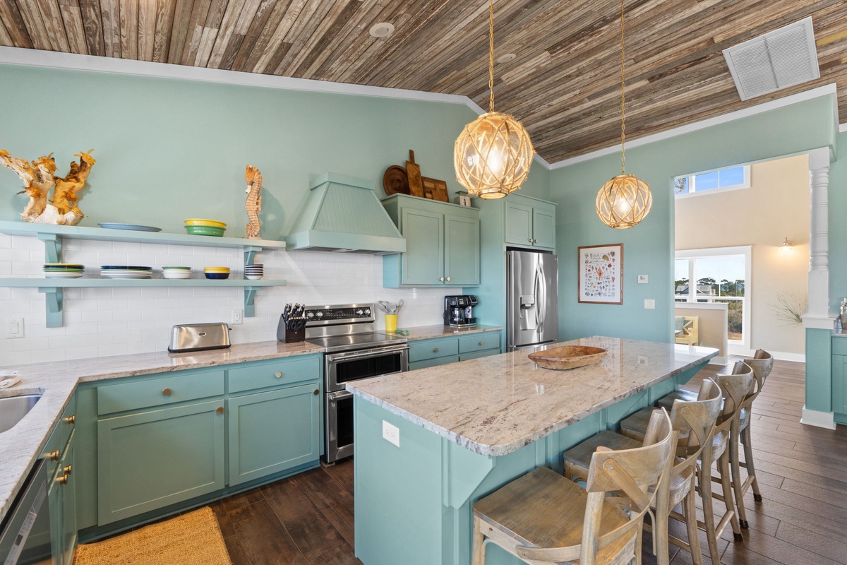 Cook together in this bright coastal kitchen with sea-glass cabinets, granite island seating, and beach-inspired decor.