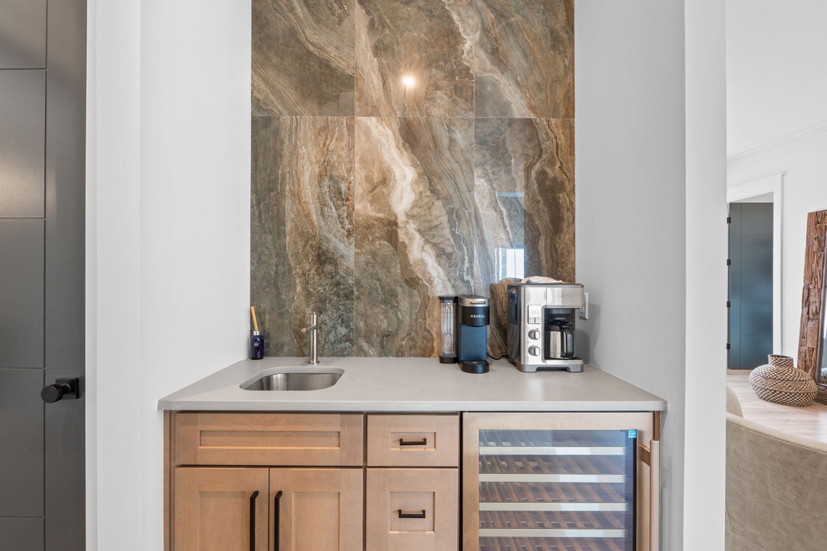 A dedicated bar nook features stunning marble, a prep sink, coffee station, and wine fridge—your perfect spot for crafting morning brews or evening cocktails.