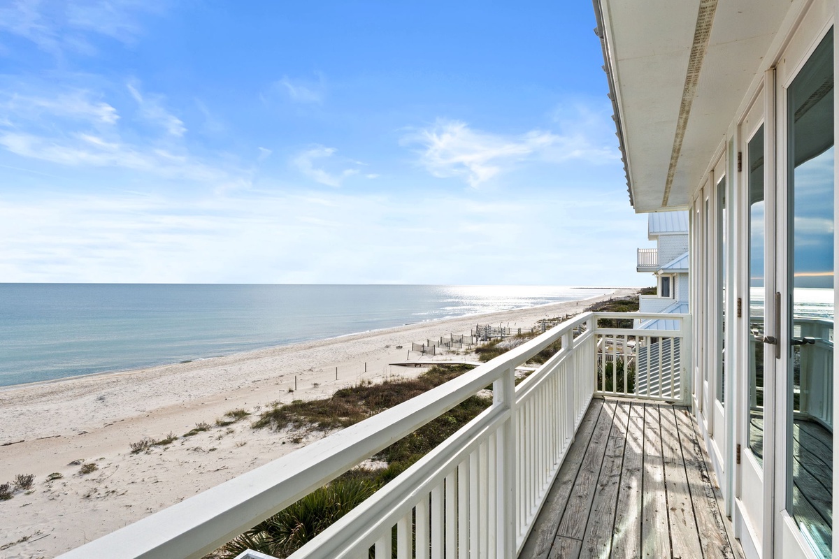Beachfront balcony with panoramic ocean views and pristine sandy shores stretching endlessly along the coast.