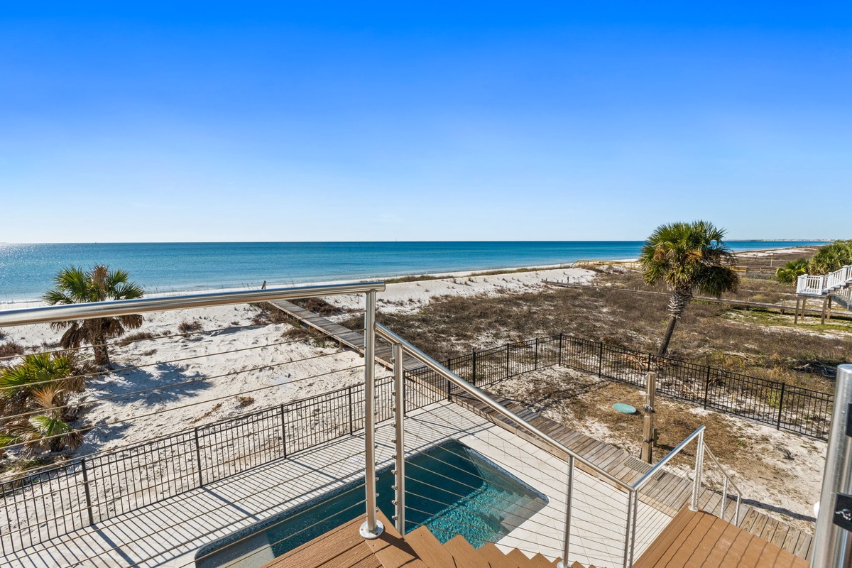 Stunning beachfront property with pristine white sand beach and turquoise waters stretching to the horizon under clear blue skies.