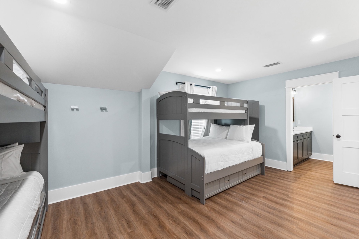 Sleep soundly in your spacious bedroom with fresh linens, modern bunk beds, and warm wood floors that make every step feel cozy and inviting.
