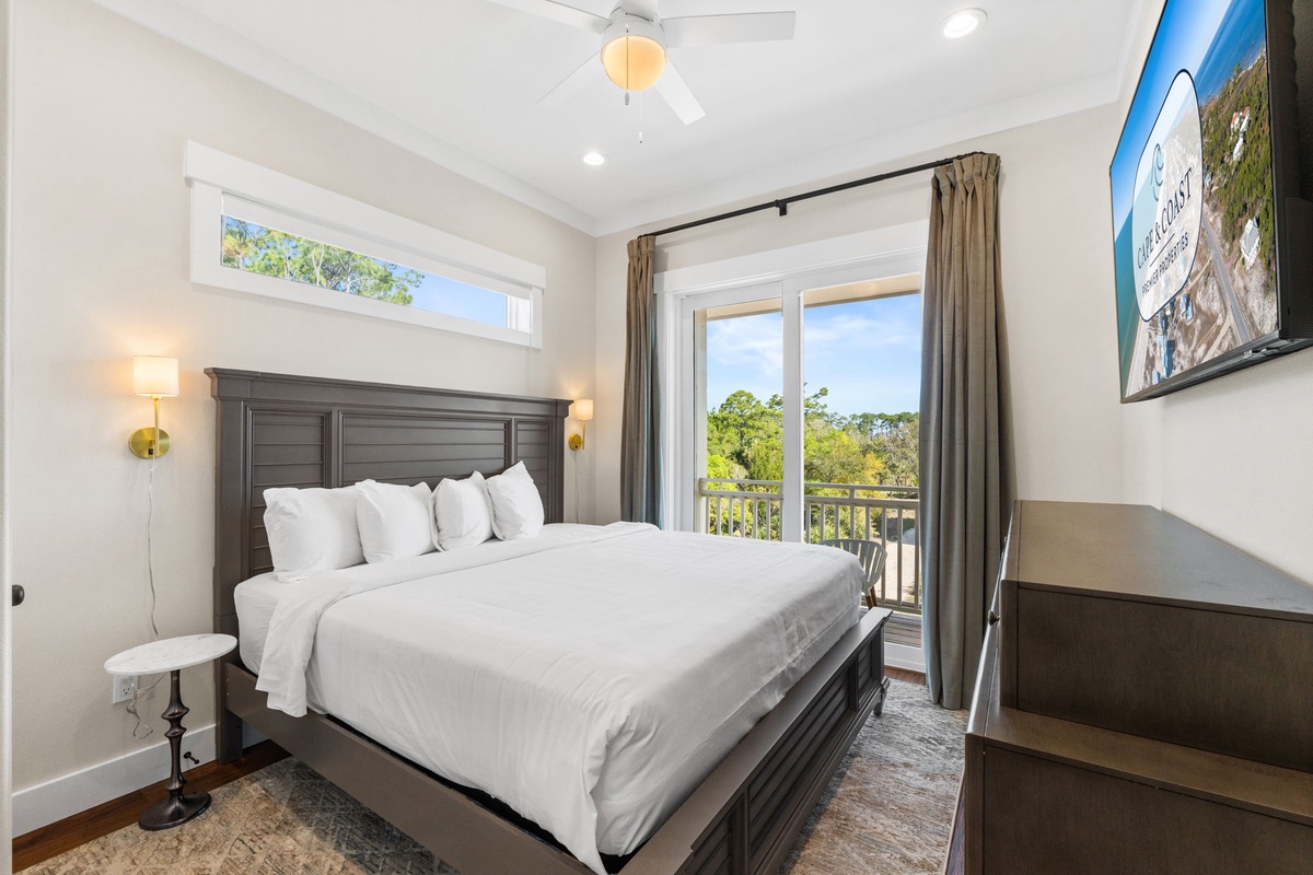 Sink into crisp white linens and wake to leafy views from your private balcony in this serene bedroom retreat.