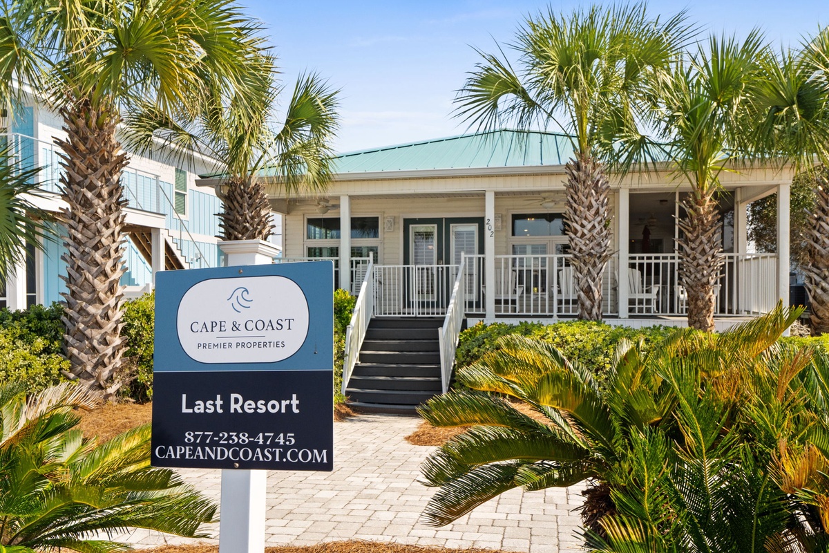 A charming beachside property nestled among swaying palm trees, with a welcoming entrance and tropical landscaping that sets the perfect coastal vacation mood.