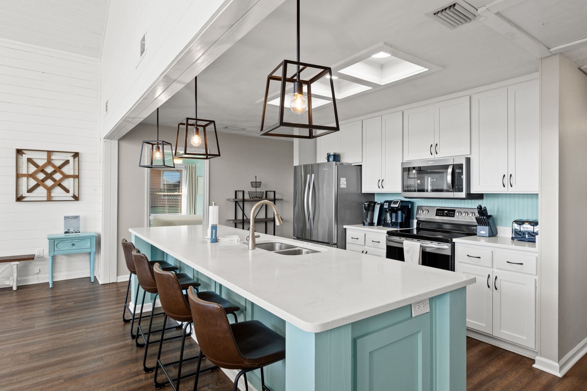 Your spacious kitchen features a stunning turquoise island with seating for four, modern pendant lighting, and stainless steel appliances for all your culinary adventures.