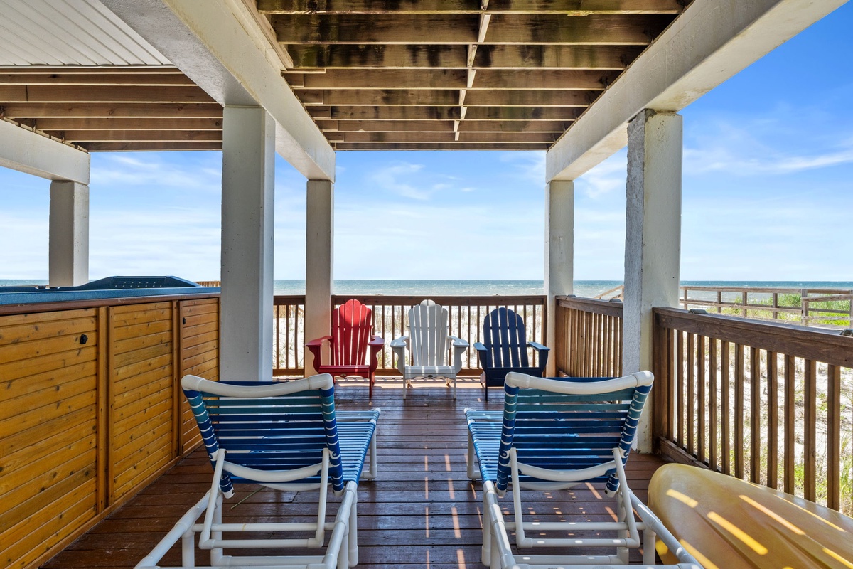 Unobstructed ocean views greet you from this covered beachfront deck, featuring colorful Adirondack chairs and lounge seating for soaking up the coastal breeze and scenery.