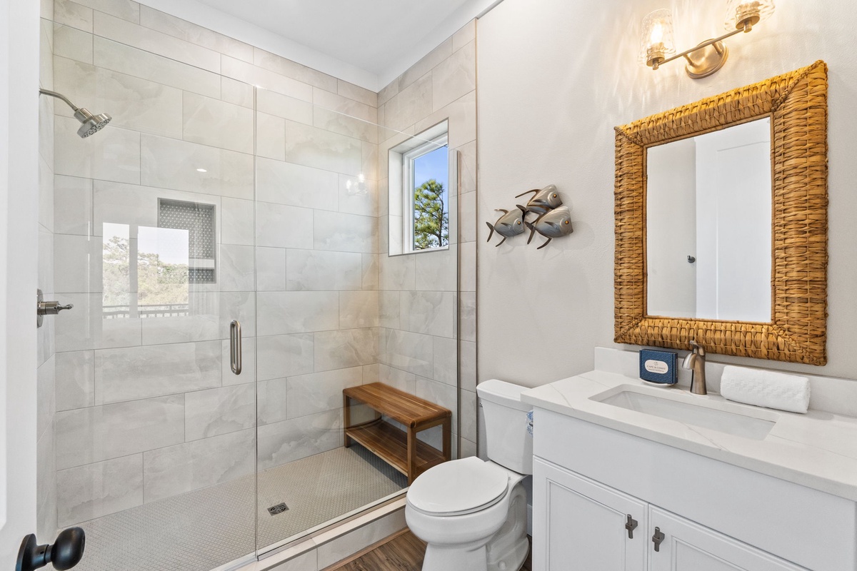 Step into your spa-like bathroom featuring a spacious glass shower, coastal décor, and warm lighting for ultimate relaxation.