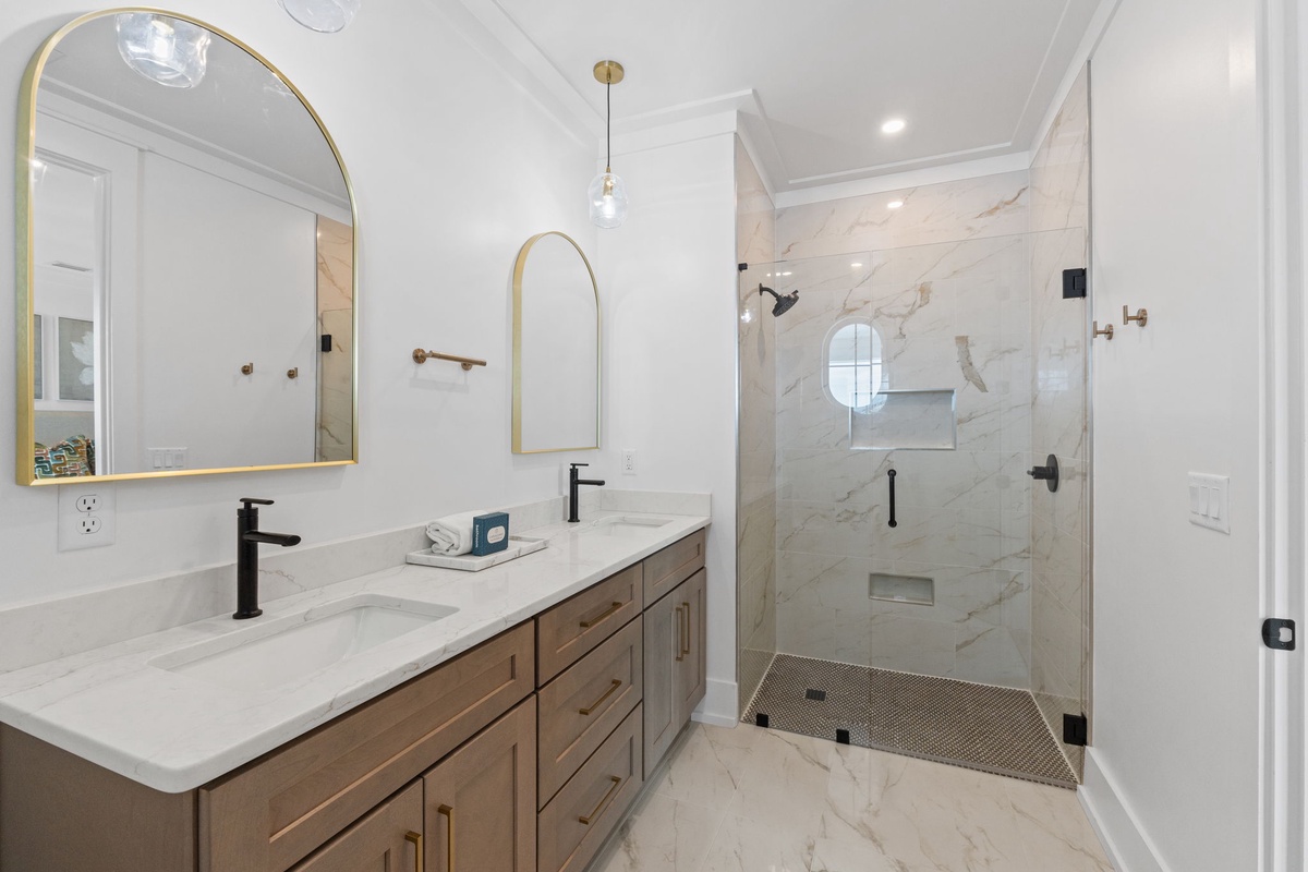 Your luxurious bathroom features elegant marble surfaces, a spacious walk-in shower, and sophisticated gold accents that create a spa-like retreat.