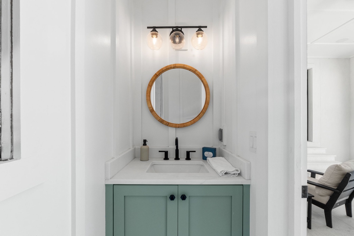 Freshen up in your beautifully designed bathroom, featuring a charming mint-green vanity, warm wood accents, and elegant lighting that creates a serene, spa-like retreat.