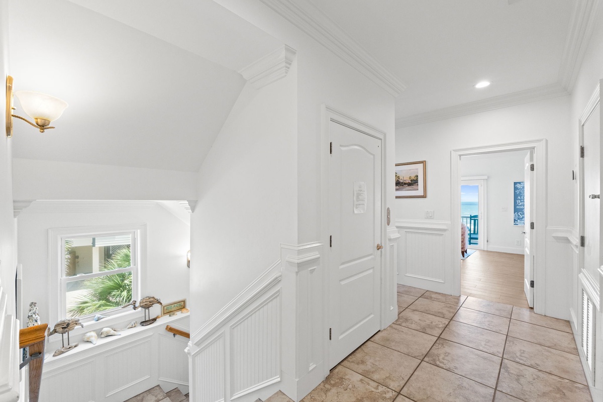 Stepping inside, you'll find a bright hallway connecting the peaceful rooms of your coastal retreat, with glimpses of the shimmering sea beyond.