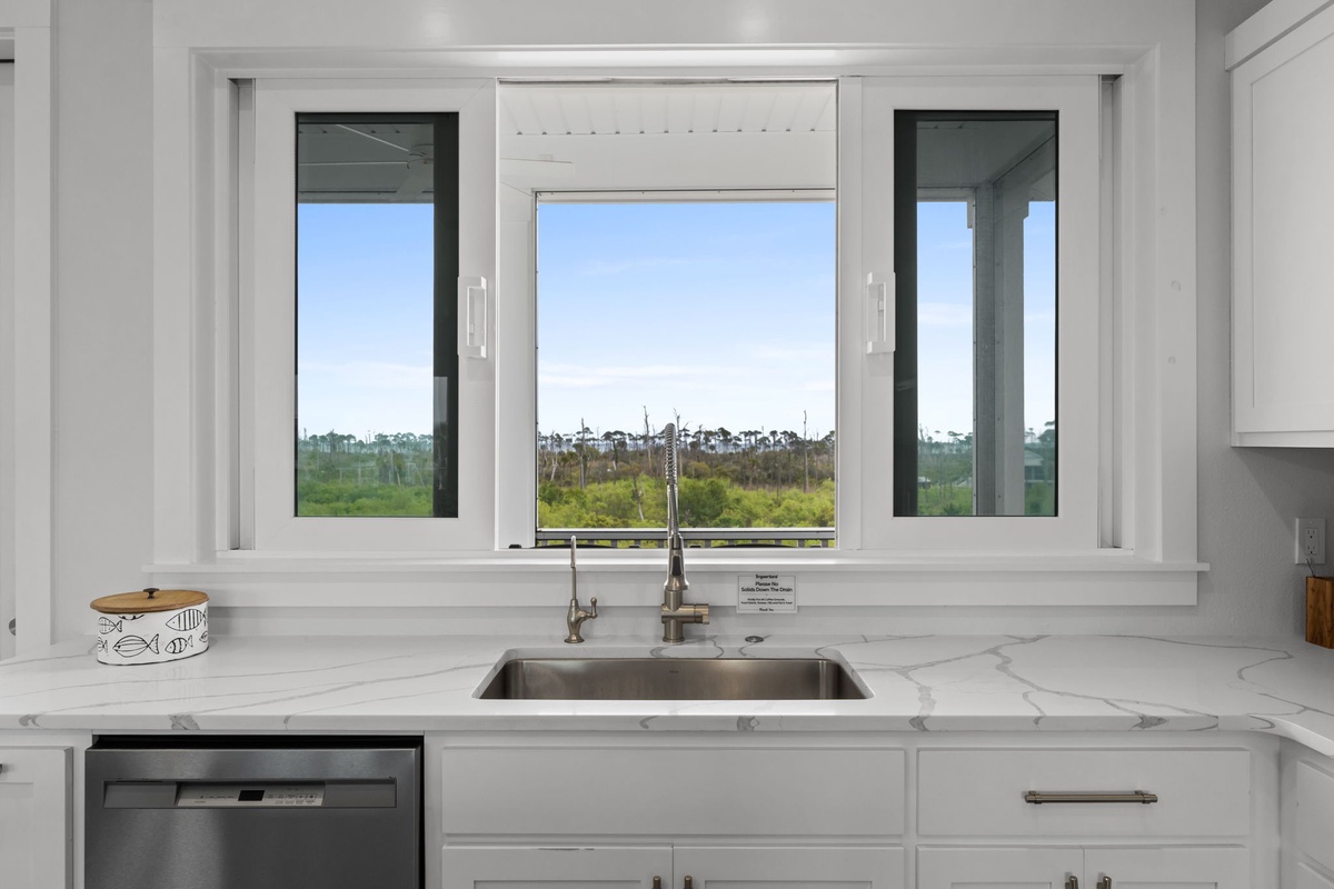 Prepare meals while gazing out at peaceful landscape views from your bright, modern kitchen with pristine marble countertops and premium appliances.