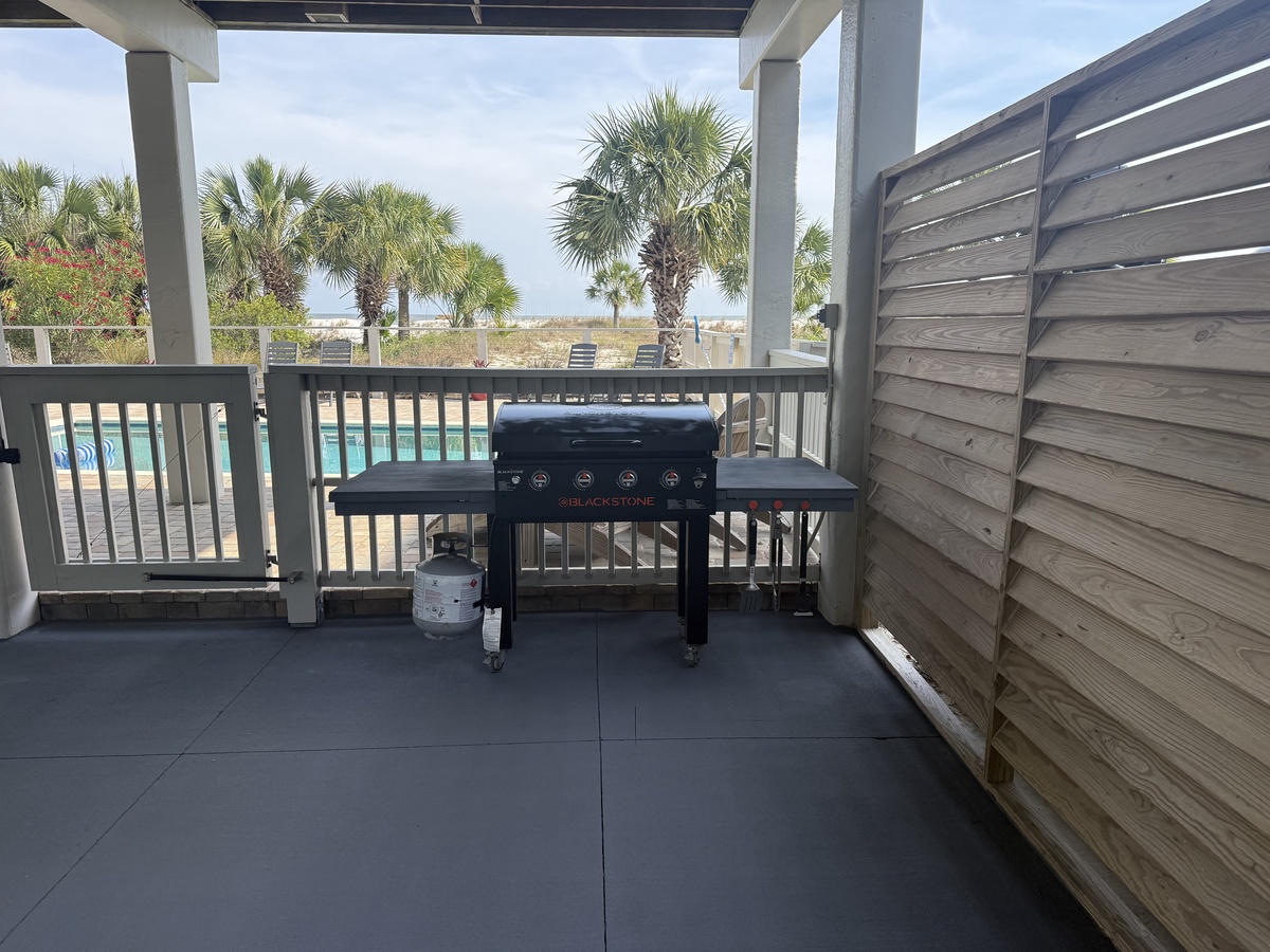 Your private balcony features a spacious Blackstone grill, perfect for cooking fresh meals while enjoying poolside and palm tree views—an ideal spot for outdoor dining.