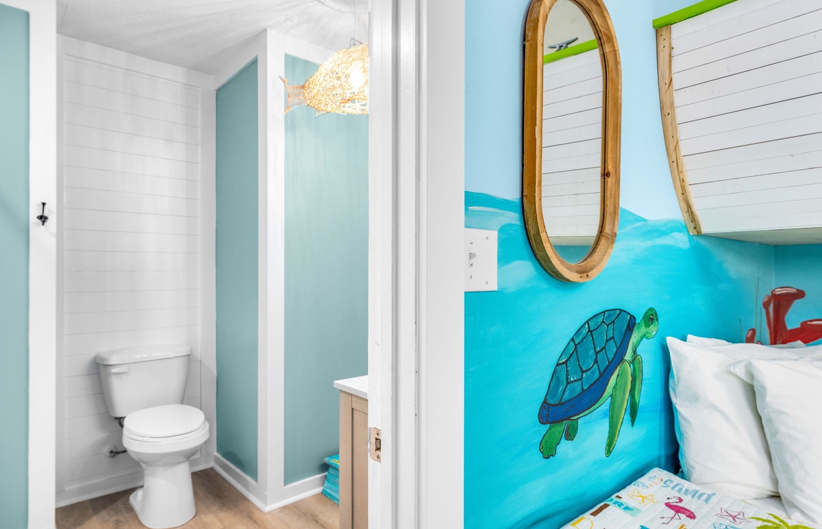 Your coastal-themed bedroom features ocean-blue walls with sea turtle art, while the private bathroom offers modern convenience in this charming seaside retreat.