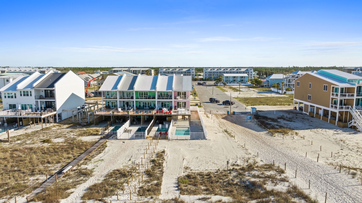 Coastal community featuring modern beachfront homes with swimming pools and sandy pathways leading to pristine shoreline access.